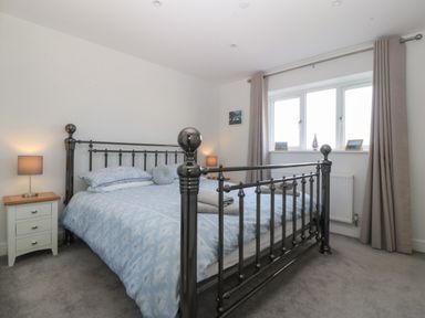 A bedroom with a metal bed frame blue bedding and nightstands with lamps at Hedd in Amlwch