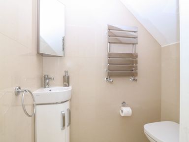 A bathroom with a sink cabinet mirror towel ring towel rail toilet and toilet paper holder at Hedd in Amlwch