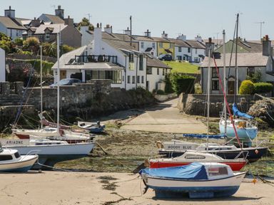 A small harbor with sailboats docked near houses along the waterfront at Hedd in Amlwch
