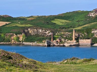 A coastal landscape with old brick ruins and chimneys by the water at Hedd in Amlwch