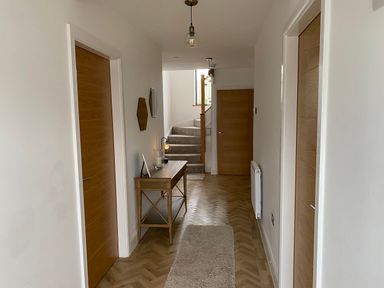 A hallway with wooden doors a wooden console table mirrors and stairs at Galwad y Mor in Broad Haven
