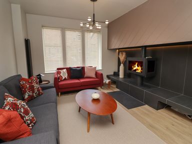 A living room with a gray sofa a red sofa a wooden coffee table and a fireplace at Glencoe House in Wooler