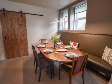A dining room with a wooden table set for six people and chairs around it at Glencoe House in Wooler