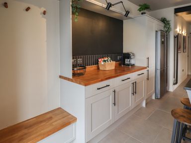 A kitchen with wooden countertops white cabinets a coffee machine and a refrigerator at Glencoe House in Wooler