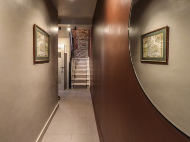 A narrow hallway with a carpeted staircase and framed artwork reflected in a large round mirror at Glencoe House in Wooler
