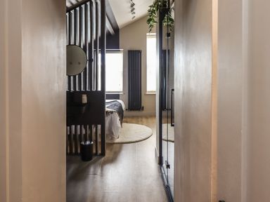 A view down a hallway into a bedroom with a bed a round rug and vertical black radiator at Glencoe House in Wooler