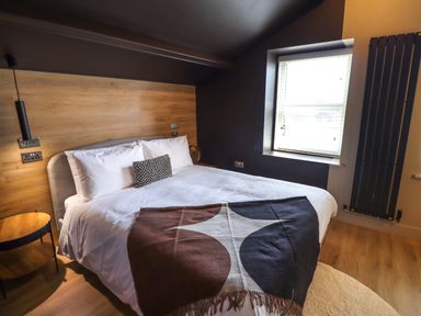 A bedroom with a double bed a window and a radiator at Glencoe House in Wooler