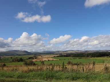 A rural landscape with fields trees and hills under a partly cloudy sky at Glencoe House in Wooler
