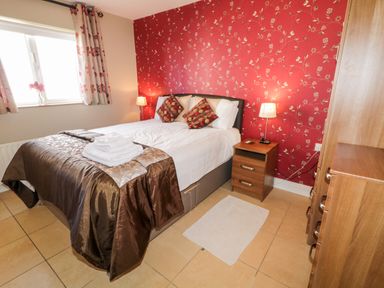 A bedroom with a double bed bedside tables lamps and a wardrobe at Inverbeg Cottage 1 in Downings