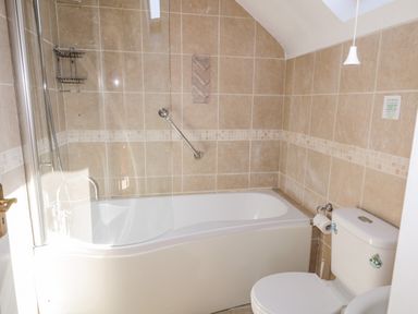 A bathroom with a bathtub shower combination and a toilet at Inverbeg Cottage 1 in Downings