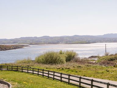 A river with hills in the background and a wooden fence along a path at Inverbeg Cottage 1 in Downings