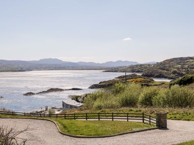 A coastal view with hills and a house near the water at Inverbeg Cottage 1 in Downings