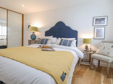 A bedroom with a blue headboard yellow throw blanket bedside tables lamps and a chair at The Gallivant in Southwold