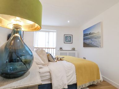 A bedroom with a bed a blue glass lamp and framed pictures on walls at The Gallivant in Southwold