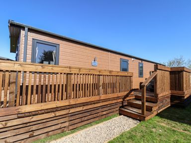 Exterior view of a wooden lodge with a deck and stairs leading up at Mayflower Lodge in Runswick Bay near Staithes