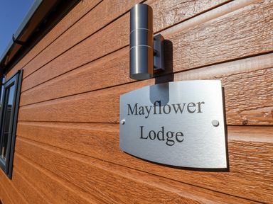 A metal sign reading Mayflower Lodge on a wooden exterior wall near a black window frame at Mayflower Lodge in Runswick Bay near Staithes