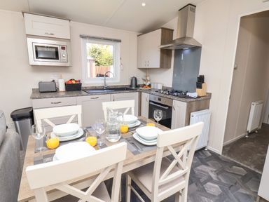 A kitchen and dining area with set table and appliances at Mayflower Lodge in Runswick Bay near Staithes