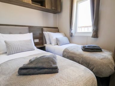 A bedroom with two single beds each with folded towels on a blanket at Mayflower Lodge in Runswick Bay near Staithes