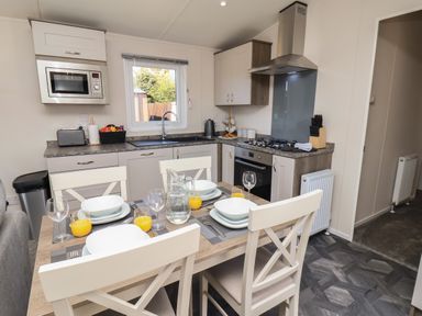 A kitchen with a dining table set for four with plates and glasses at Foxglove Lodge in Runswick Bay near Staithes