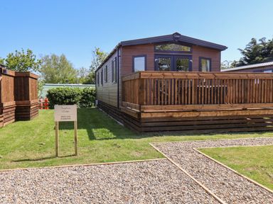 A wooden lodge with a deck and private parking sign on grass at Foxglove Lodge in Runswick Bay near Staithes
