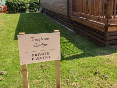 A lawn with a wooden sign saying Foxglove Lodge private parking next to a wooden building at Foxglove Lodge in Runswick Bay near Staithes