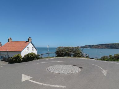 A view of a house near the sea with a roundabout in the foreground at Foxglove Lodge Runswick Bay near Staithes