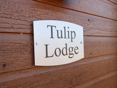A metal sign with the words Tulip Lodge mounted on wooden siding at Tulip Lodge in Runswick Bay near Staithes