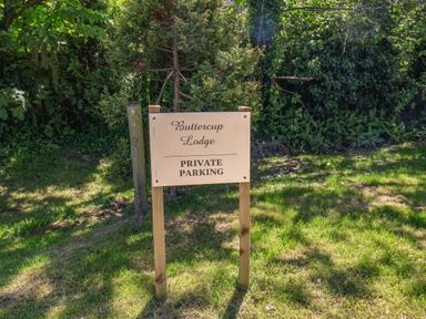 A sign that says Buttercup Lodge private parking on grass with bushes in the background at Buttercup Lodge in Runswick Bay near Staithes