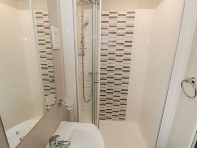 A bathroom with a sink and a shower area with patterned tiles at Rose Lodge in Runswick Bay near Staithes