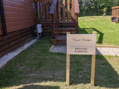 A wooden deck with steps and a private parking sign on grass at Rose Lodge in Runswick Bay near Staithes