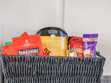 A woven basket with packets of Yorkshire tea Yorkshire crisps Cadbury hot chocolate and other snacks