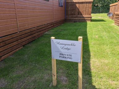 A private parking sign on grass between wooden buildings at Honeysuckle Lodge in Runswick Bay near Staithes