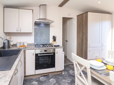 A kitchen with a gas stove oven sink countertop and dining table at Lilac Lodge in Runswick Bay near Staithes