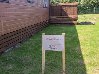 A sign on grass indicating private parking next to a wooden building at Lilac Lodge in Runswick Bay near Staithes