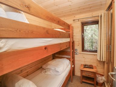 A bedroom with wooden bunk beds window and a small wooden side table at Canadian Cabin 37 in Keswick