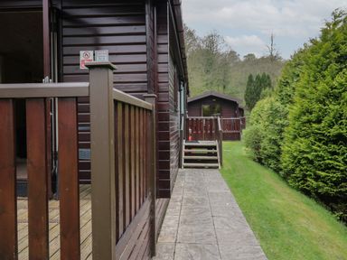 A pathway with stone tiles next to wooden cabins and green bushes at Canadian Cabin 37 in Keswick