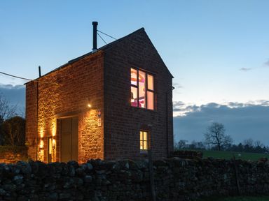 A stone house illuminated at dusk with a stone wall in front and fields in the background at Shepherds View in Dufton near Appleby-in-Westmorland