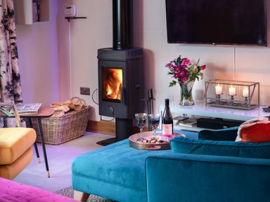 A living room with a wood burning stove flowers on a table and candles at Shepherds View Dufton near Appleby in Westmorland