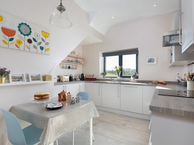 A kitchen with a table set for tea and white cabinets under a window at Shepherds View in Dufton near Appleby-in-Westmorland