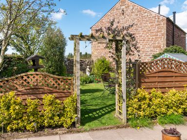 A garden entrance with wooden arch and fence with a lawn and chairs at Shepherds View Dufton near Appleby-in-Westmorland