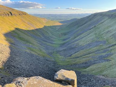 A valley with a stream flowing through grassy slopes and rocky terrain at Shepherds View in Dufton near Appleby-in-Westmorland