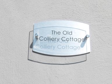 A sign on a textured wall displaying The Old Colliery Cottage at Old Colliery Cottage in Shilbottle