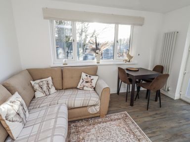 A living room with a sofa and dining area at Old Colliery Cottage in Shilbottle
