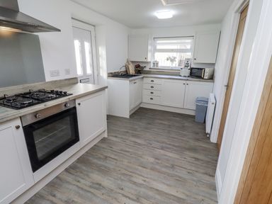 A kitchen with a gas stove and microwave at Old Colliery Cottage in Shilbottle