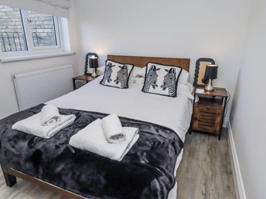 A bedroom with a bed and zebra print pillows at Old Colliery Cottage in Shilbottle