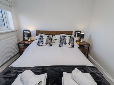 A bedroom with a bed and bedside tables at Old Colliery Cottage in Shilbottle