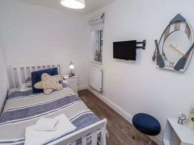 A bedroom with a bed and a wall-mounted television at Old Colliery Cottage in Shilbottle