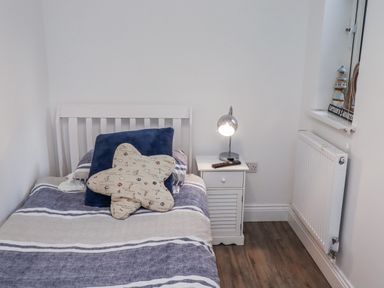 A bedroom with a bed and bedside table at Old Colliery Cottage in Shilbottle