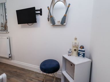 A living room with a television and decorative items at Old Colliery Cottage in Shilbottle