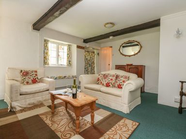 A living room with sofas coffee table and a cabinet at Thatch Cottage in Buckland Newton